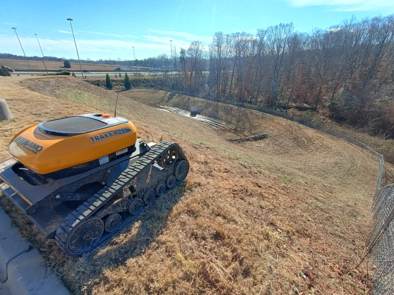 Retention pond mowing completed in Greenville SC with clean slopes and remote controlled slope mower on site