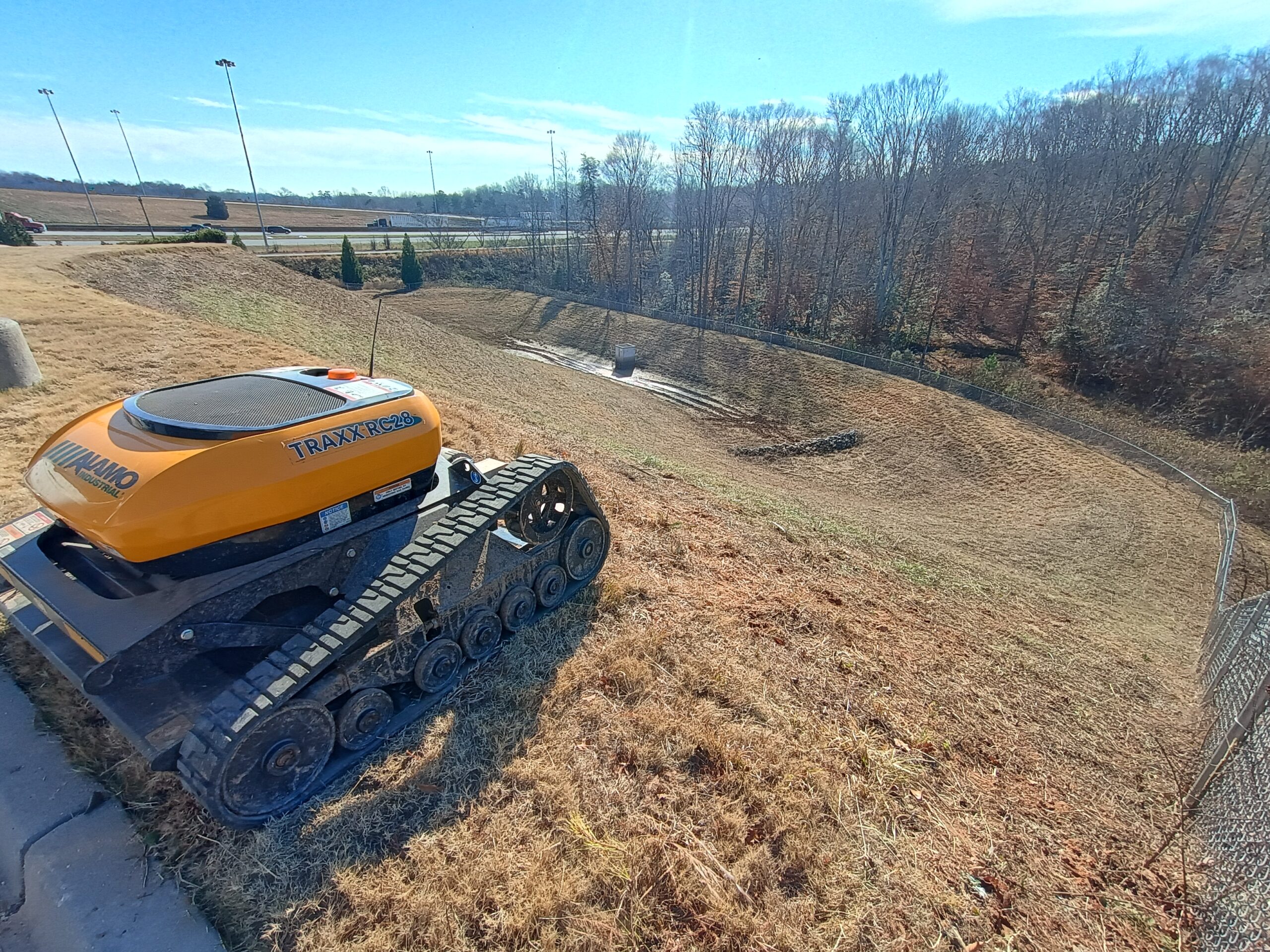 Retention pond mowing completed in Greenville SC with clean slopes and remote controlled slope mower on site
