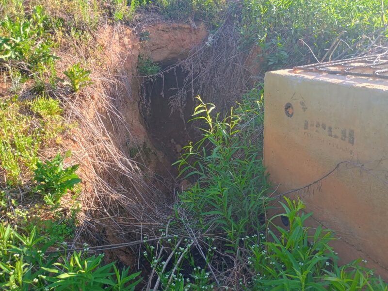 Erosion and soil collapse around retention pond drain pipe caused by lack of maintenance and overgrowth