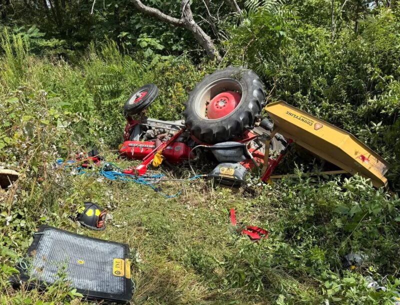 Overturned tractor on a steep slope after mowing accident in overgrown terrain